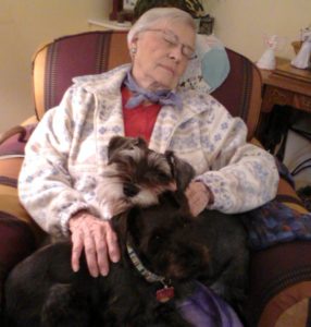 An elderly woman sleeps with her dogs