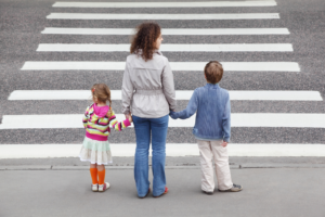 Woman crosses the street with her children