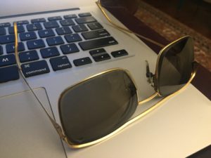 Square shaped sunglasses placed on a laptop